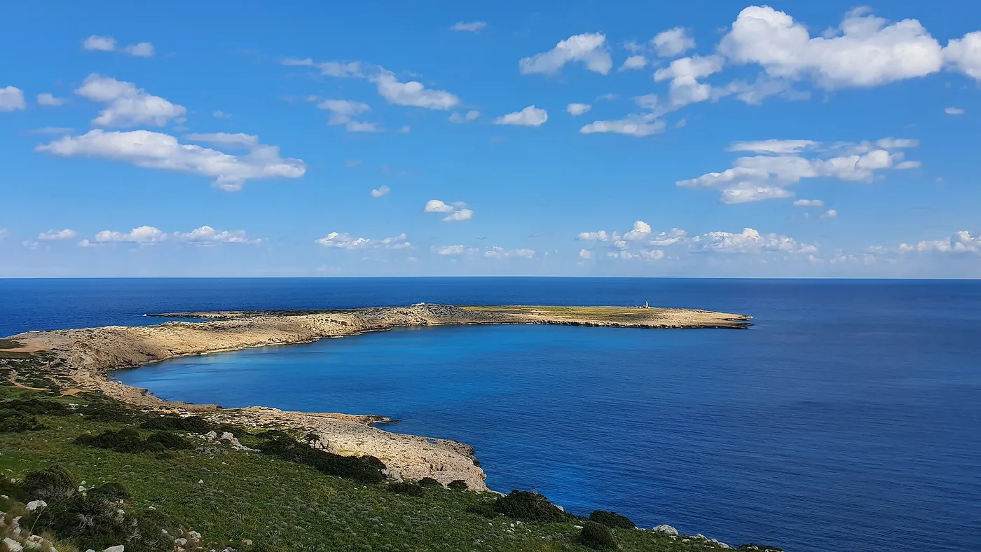 The long low headland of Cape Greco stretching into a calm, deep blue sea