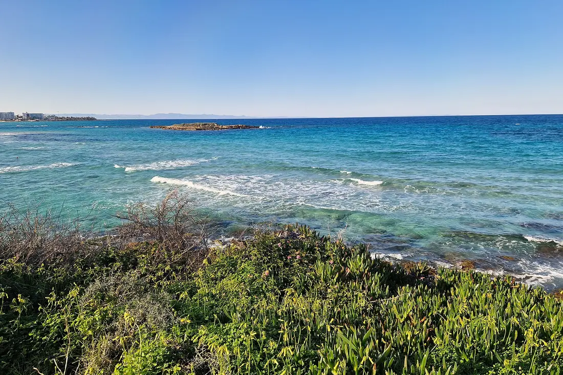 Waves breaking on the green coast near Protaras with a distant headland on the horizon